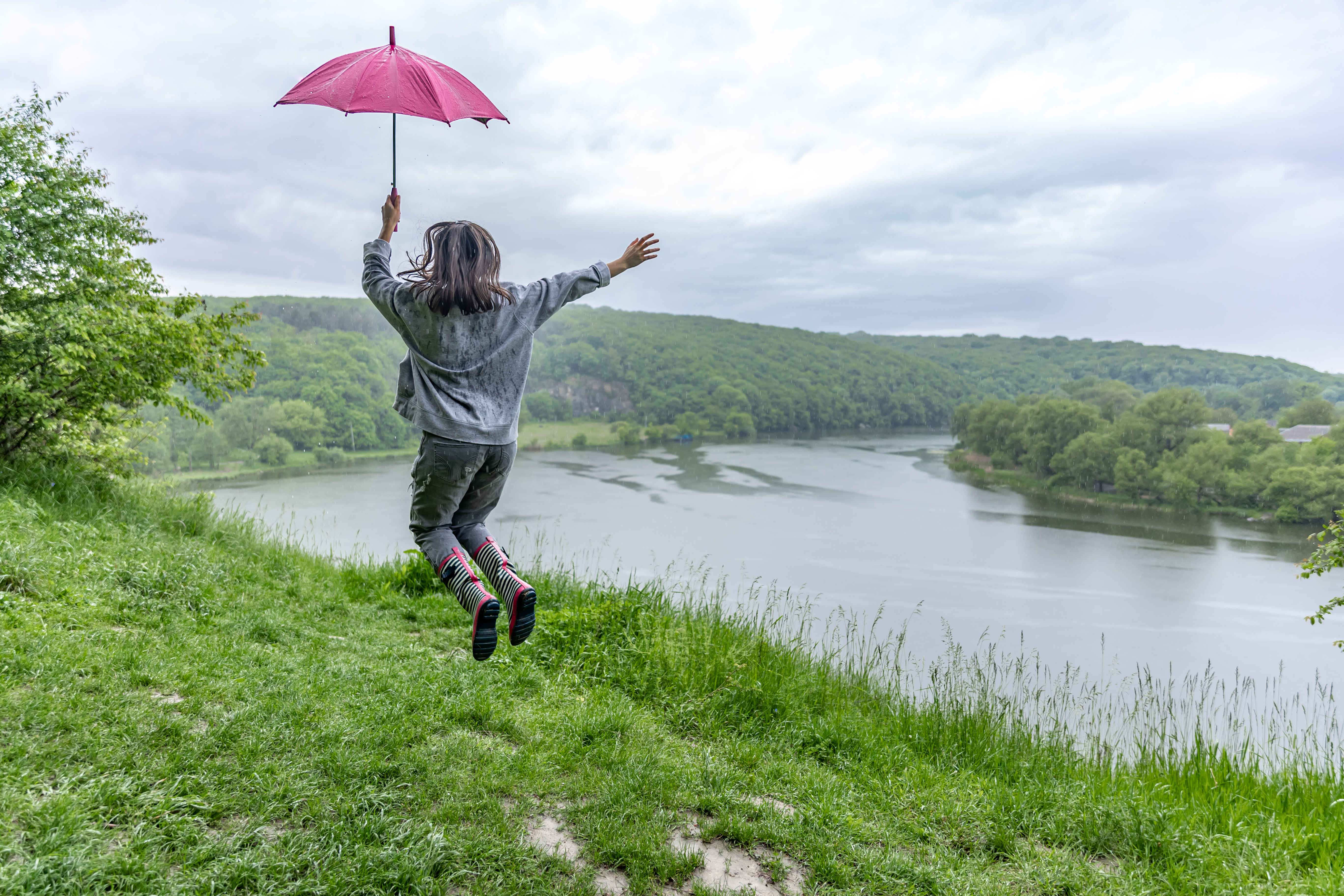 back-view-girl-umbrella-jumping-near-lake-mountainous-area-rainy-weather